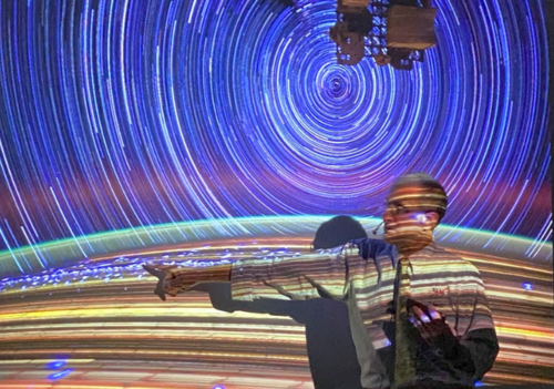 Astronaut Don Pettit stands and gestures in front of one of the images featured in the exhibition. Space Photography. Image Credit Peter Blacksberg.